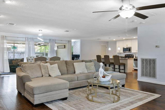 living room featuring ceiling fan, a textured ceiling, and dark hardwood / wood-style flooring