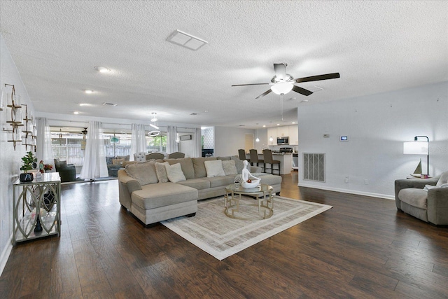 living room with dark wood-type flooring, ceiling fan, and a textured ceiling