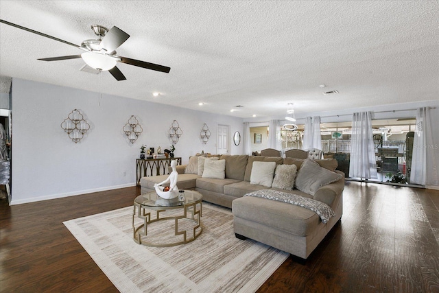 living room featuring dark wood-type flooring, ceiling fan, and a textured ceiling