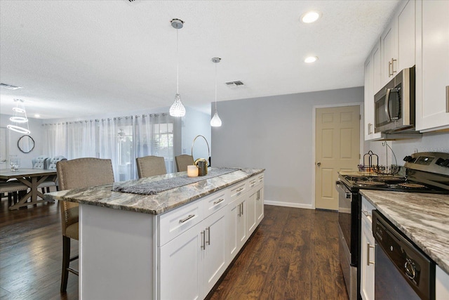 kitchen featuring light stone counters, stainless steel appliances, a center island with sink, and white cabinets