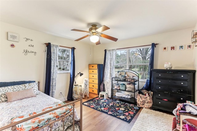 bedroom with multiple windows, hardwood / wood-style flooring, and ceiling fan