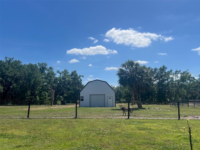 view of yard featuring fence, an outdoor structure, a garage, a barn, and a rural view