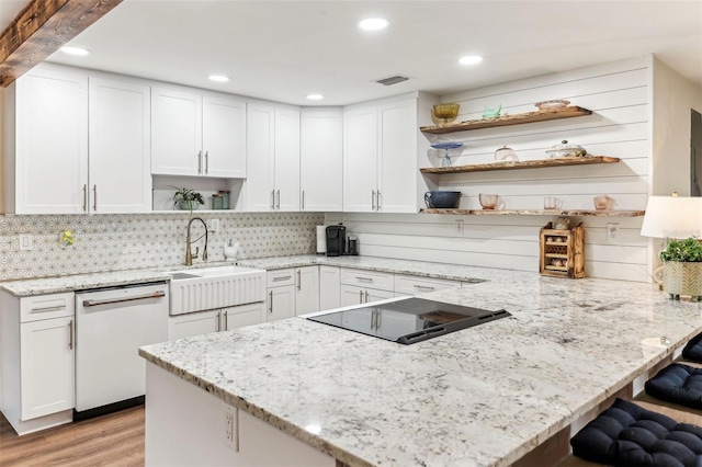 kitchen featuring a sink, a peninsula, open shelves, white cabinetry, and white dishwasher