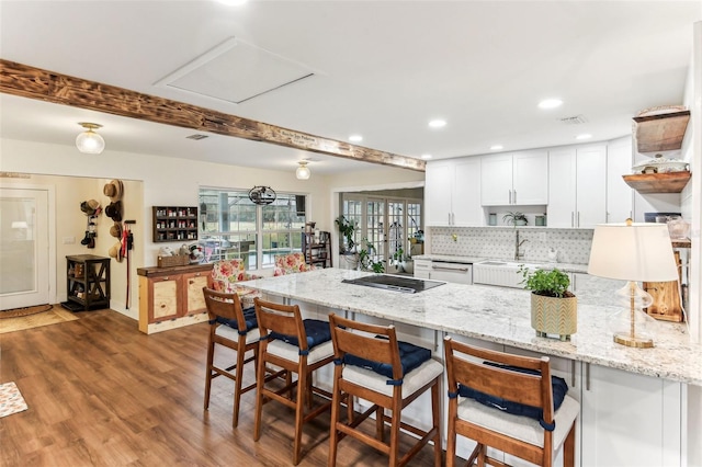 kitchen featuring a peninsula, wood finished floors, a breakfast bar, open shelves, and white cabinetry