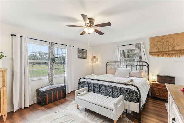 bedroom with dark wood-style floors, a ceiling fan, and multiple windows