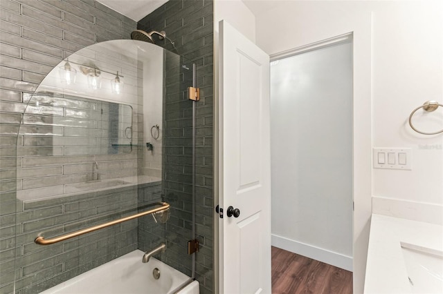 bathroom featuring baseboards, wood finished floors, and shower / bathing tub combination