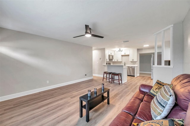 living room featuring ceiling fan and light hardwood / wood-style floors