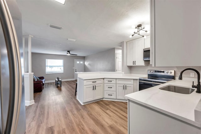 kitchen featuring white cabinets, kitchen peninsula, sink, and stainless steel appliances