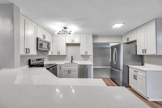 kitchen featuring light stone countertops, white cabinetry, sink, and stainless steel appliances