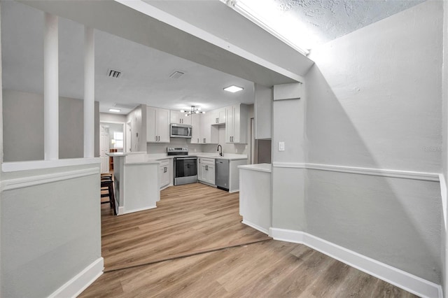 kitchen featuring a textured ceiling, white cabinetry, stainless steel appliances, sink, and light hardwood / wood-style flooring