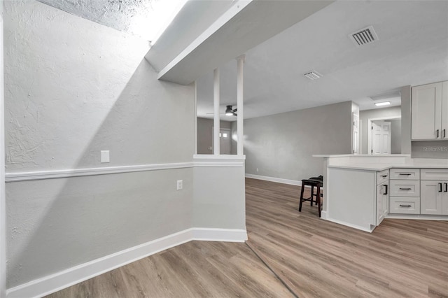 kitchen featuring ceiling fan, white cabinetry, and light hardwood / wood-style flooring