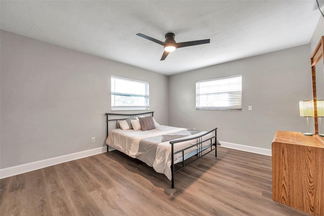 bedroom featuring ceiling fan, dark wood-type flooring, and multiple windows