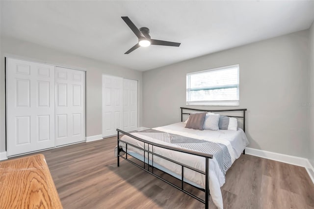 bedroom with ceiling fan, dark wood-type flooring, and two closets