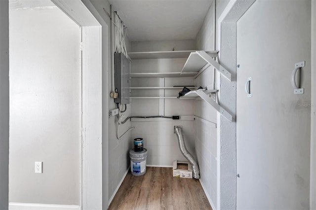 clothes washing area with electric panel and wood-type flooring