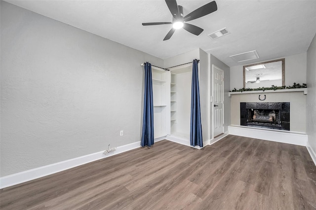 unfurnished living room with a textured ceiling, built in features, hardwood / wood-style floors, and a tile fireplace