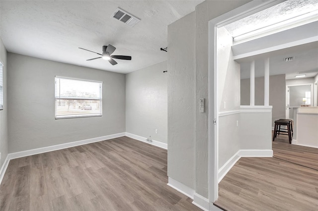 empty room featuring ceiling fan, a textured ceiling, and light wood-type flooring