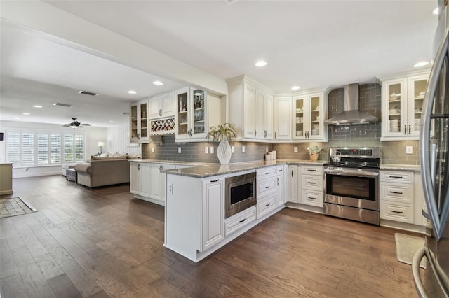 kitchen featuring wall chimney range hood, stainless steel appliances, dark hardwood / wood-style floors, light stone counters, and white cabinets