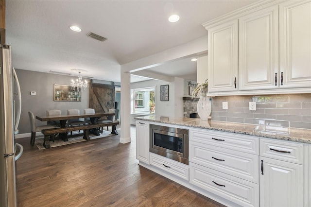 kitchen featuring white cabinetry, dark hardwood / wood-style floors, appliances with stainless steel finishes, and a barn door