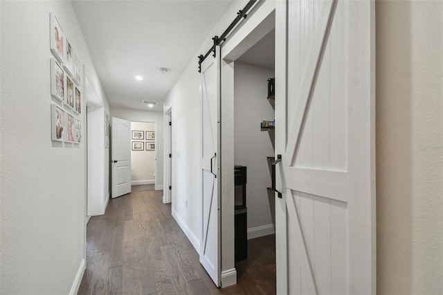 hall with a barn door and dark hardwood / wood-style flooring