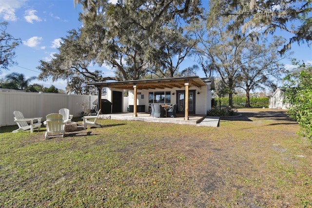 back of house featuring an outdoor fire pit, a patio area, and a lawn