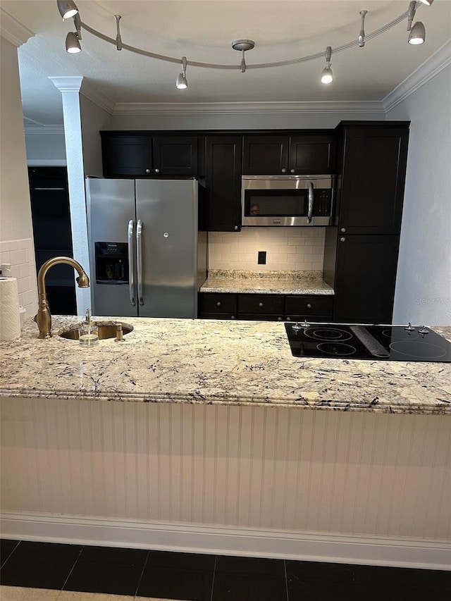 kitchen featuring sink, light stone counters, dark tile patterned flooring, stainless steel appliances, and decorative backsplash