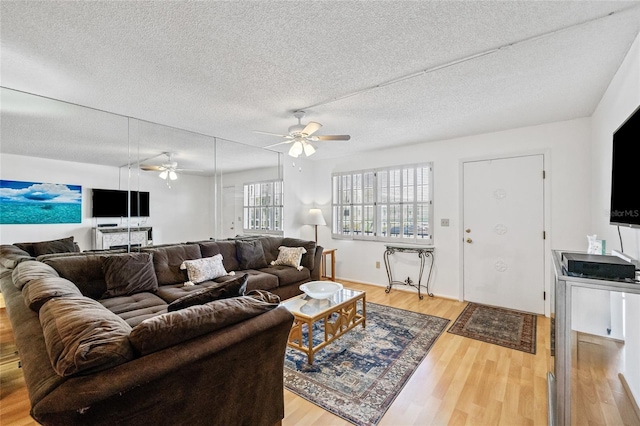 living room featuring hardwood / wood-style flooring, ceiling fan, and a textured ceiling