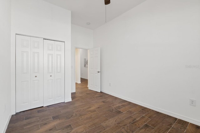 unfurnished bedroom featuring ceiling fan, a closet, and a towering ceiling