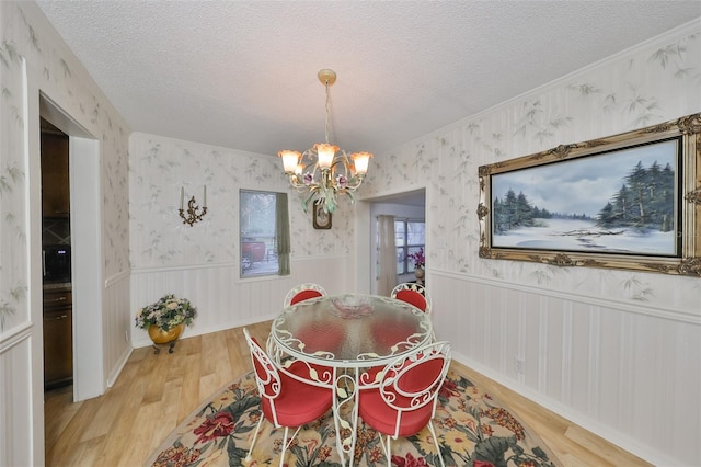 dining area featuring hardwood / wood-style flooring, a textured ceiling, and a chandelier