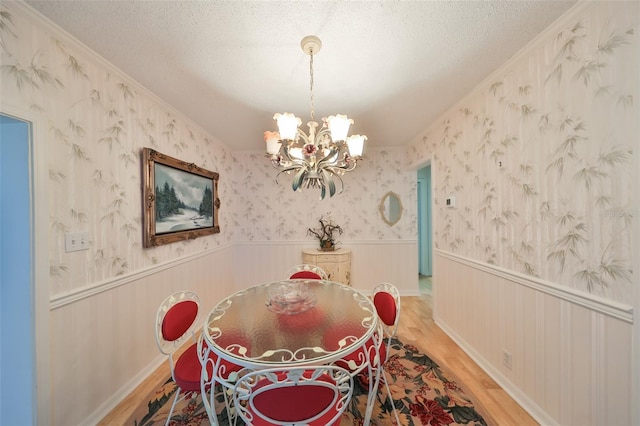 unfurnished dining area featuring ornamental molding, hardwood / wood-style floors, a textured ceiling, and a notable chandelier