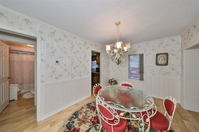 dining area featuring hardwood / wood-style flooring, a textured ceiling, and a notable chandelier