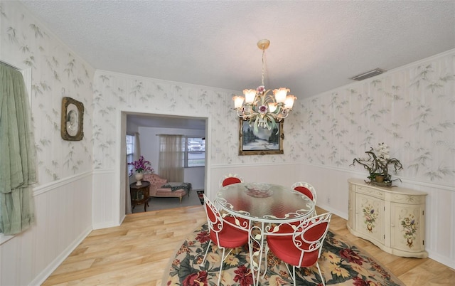 dining area with an inviting chandelier, hardwood / wood-style floors, crown molding, and a textured ceiling