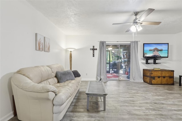 living room featuring ceiling fan, hardwood / wood-style flooring, and a textured ceiling