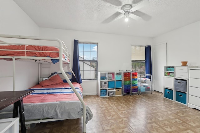 bedroom with multiple windows, ceiling fan, and a textured ceiling