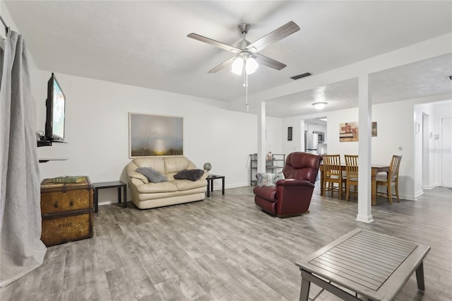 living area featuring baseboards, wood finished floors, visible vents, and a ceiling fan