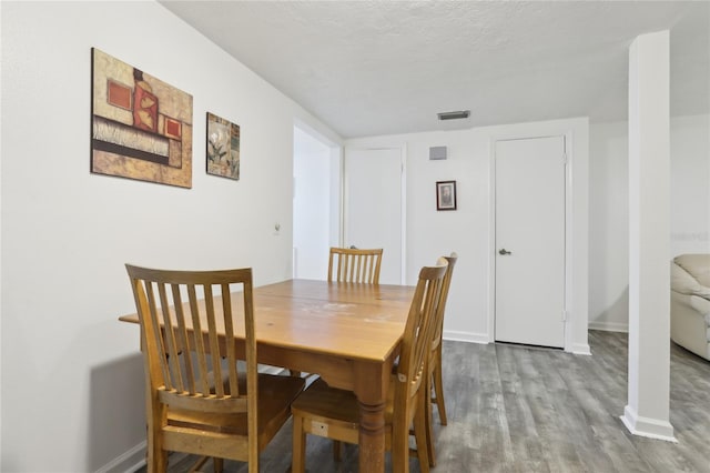 dining room featuring a textured ceiling and light wood-type flooring