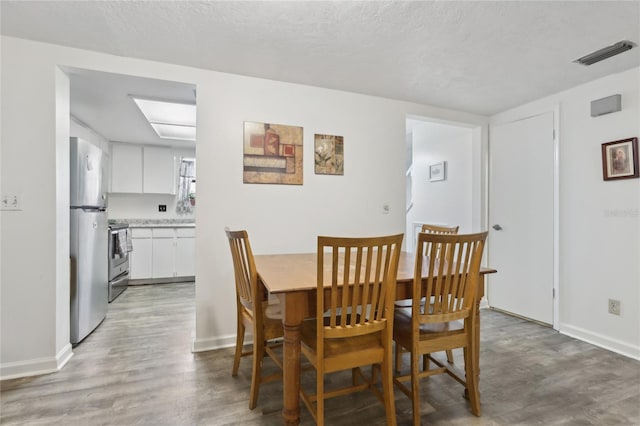 dining area featuring hardwood / wood-style flooring and a textured ceiling