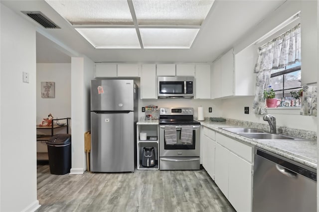 kitchen featuring white cabinetry, sink, light hardwood / wood-style flooring, and appliances with stainless steel finishes