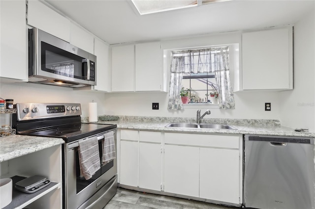 kitchen with white cabinetry, stainless steel appliances, sink, and light wood-type flooring