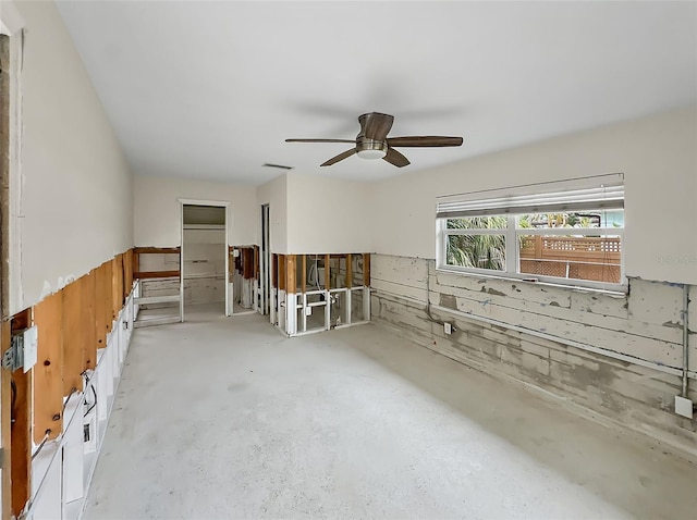 empty room with ceiling fan and wood walls