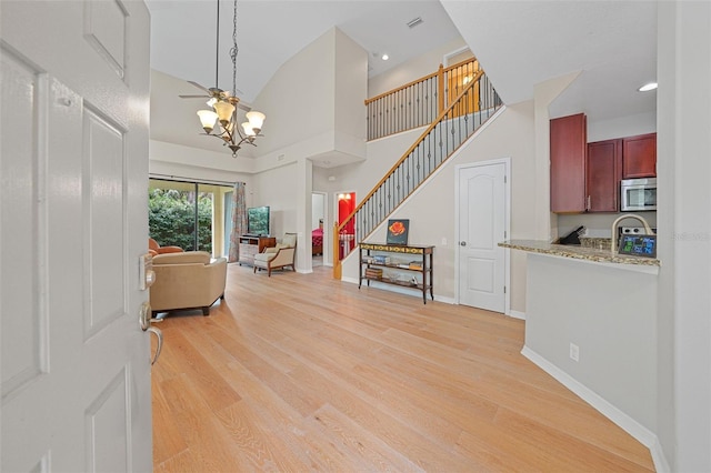 interior space with a towering ceiling, a chandelier, and light hardwood / wood-style floors