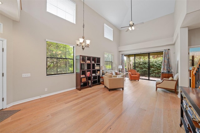 living room featuring ceiling fan with notable chandelier, light hardwood / wood-style flooring, and a healthy amount of sunlight