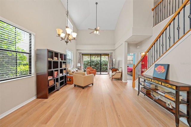 living room featuring ceiling fan with notable chandelier, high vaulted ceiling, a wealth of natural light, and light hardwood / wood-style floors