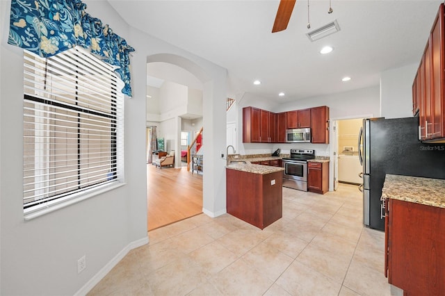 kitchen with ceiling fan, stainless steel appliances, light stone countertops, and light tile patterned floors