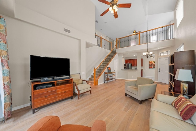 living room featuring hardwood / wood-style flooring, a towering ceiling, and ceiling fan with notable chandelier