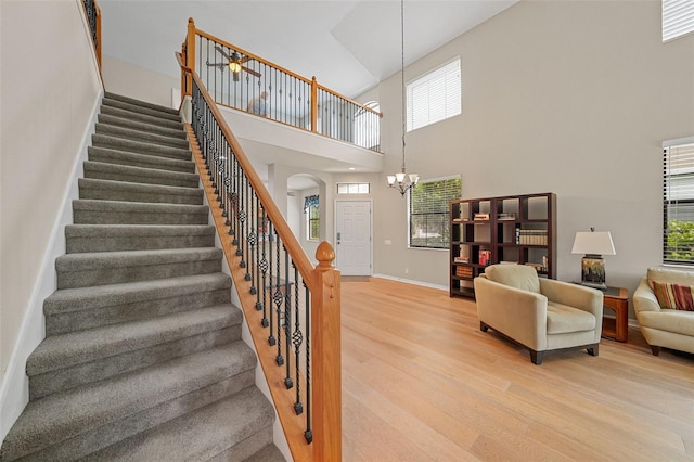 staircase with a notable chandelier, hardwood / wood-style flooring, and a high ceiling