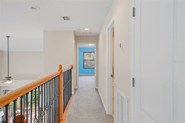 hallway featuring light carpet and a textured ceiling