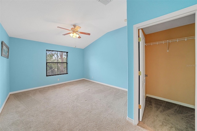 unfurnished bedroom featuring lofted ceiling, a walk in closet, carpet floors, a closet, and ceiling fan