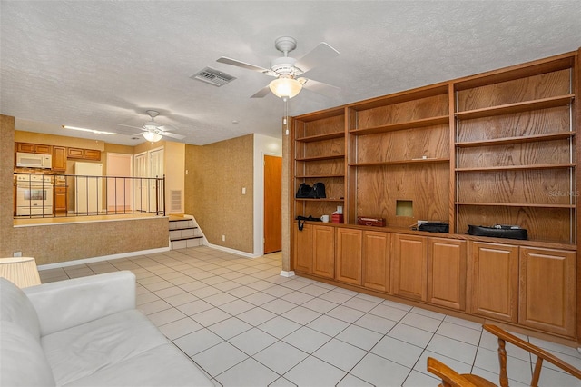 tiled living room with ceiling fan and a textured ceiling