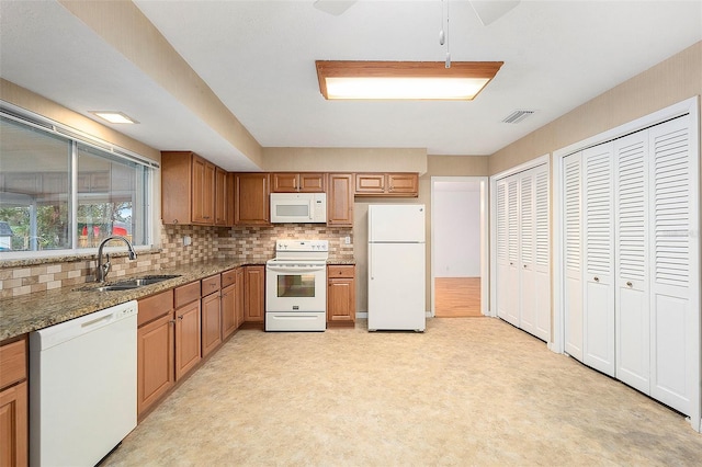 kitchen featuring stone countertops, sink, white appliances, and decorative backsplash