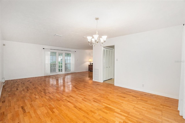 empty room featuring an inviting chandelier and light wood-type flooring